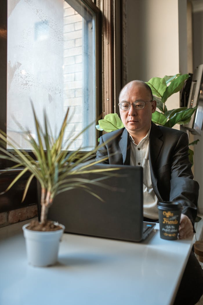 Man in Black Suit Sitting Beside Table